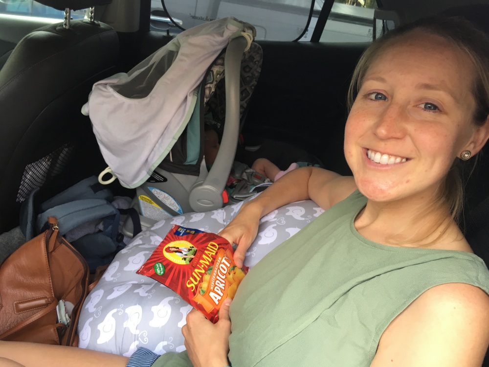 Woman sitting in a car with a snack bag, Sun-Maid dried fruit pack in hand